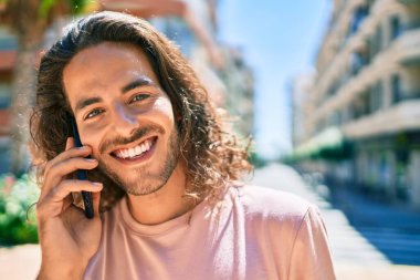 Genç İspanyol adam gülümsüyor. Şehirdeki akıllı telefondan konuşuyor..