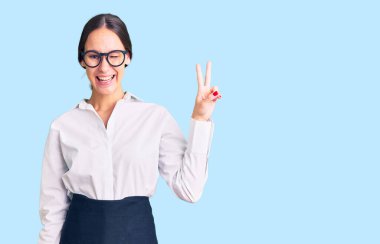 Güzel esmer, profesyonel garson önlüğü giyen, kameraya gülümseyen ve parmaklarıyla zafer işareti yapan genç bir kadın. İki numara.. 