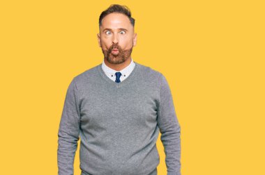 İş kıyafetleri giymiş yakışıklı orta yaşlı bir adam dudaklarıyla balık suratı yapıyor, çılgınca ve komik bir jest. Komik ifade. 