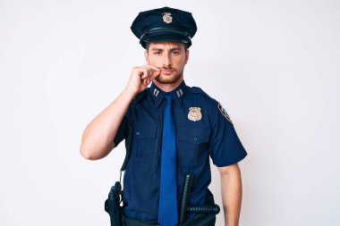 Polis üniforması giyen genç, beyaz bir adam ağzı ve dudakları parmaklarıyla fermuar gibi kapalı. gizli ve sessiz, tabu konuşması 