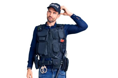 Polis üniforması giyen genç yakışıklı adamın kafası karışıyor ve soru sormayı merak ediyor. Şüpheyle kararsız, kafa kafaya düşünerek. Düşünceli kavram. 