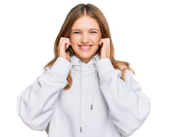 Gürültülü müzik sesi için kulaklarını parmaklarıyla kapatan sıradan bir kazak giyen güzel beyaz bir kız. sağır kavramı. 