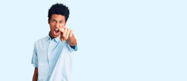 Genç, Afro-Amerikan bir adam, gündelik giysiler içinde kameraya kızgın ve hayal kırıklığına uğramış bir şekilde bakıyor. 