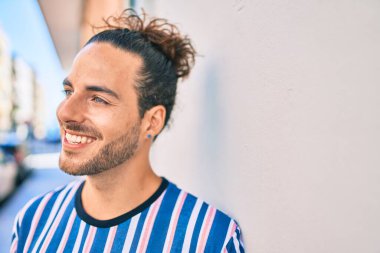 Genç İspanyol adam gülümsüyor. Mutlulukla duvara bakıyor.