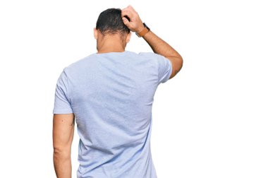 Latin asıllı genç adam gündelik kıyafetleri ters giyip elleri kafasında şüpheyi düşünüyor. 