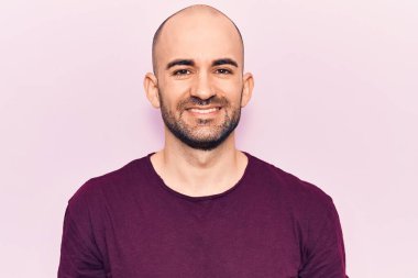 Genç, yakışıklı, kel, sıradan tişörtler giyen mutlu ve havalı bir gülümsemesi olan bir adam. şanslı kişi. 