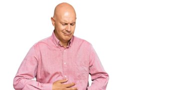 Orta yaşlı kel bir adam elleri karnında günlük kıyafetler giyiyor çünkü hazımsızlık, acı verici bir hastalık kendini iyi hissetmiyor. Ağrı kavramı. 