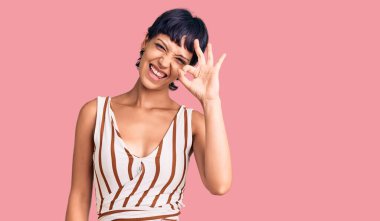 Kısa saçlı, yaz kıyafeti giyen, gülümseyen, el ve parmaklarıyla 