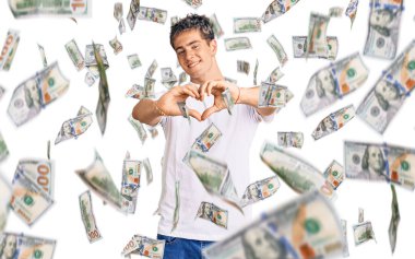 Gündelik beyaz tişört giyen, aşık gülümseyen ve elleriyle kalp sembolü yapan genç yakışıklı bir adam. romantik kavram.