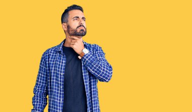 Günlük giysiler giyen genç İspanyol adam ağrılı boyuna dokunuyor, grip, mantar ve enfeksiyon yüzünden boğaz ağrısı çekiyor. 