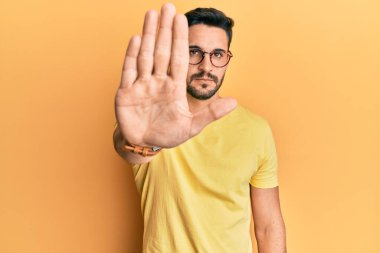 Günlük kıyafetler giyen ve gözlük takan İspanyol genç adam avucunun içi gibi şarkı söylemeyi kesiyor. Yüzünde olumsuz ve ciddi bir jest olan uyarı ifadesi. 