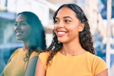 Genç Afrikalı Amerikalı kız gülümsüyor. Mutlu mesut şehrin duvarına yaslanıyor..