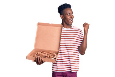 Genç Afrikalı Amerikalı bir adam elinde pizza kutusuyla başparmağını kaldırıyor ve ağzı açık gülümsüyor. 