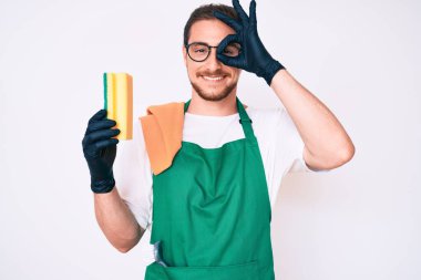 Önlük takan yakışıklı adam gülümseyen adam gülümsüyor. Tamam işaret parmağından bakıyor. 