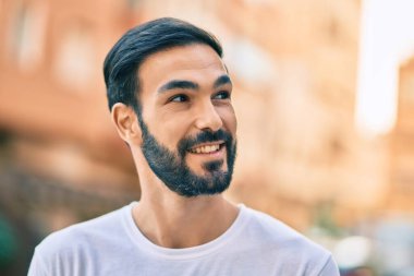 Genç İspanyol adam gülümseyerek şehirde mutlu mesut dikiliyor..