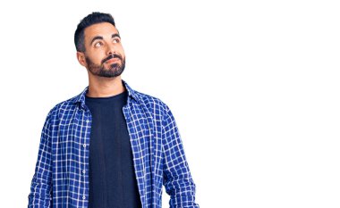 Gündelik kıyafetler giyen genç İspanyol adam gülümseyip yan tarafa bakıyor ve düşünüyor.. 