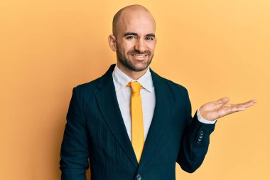 Genç İspanyol takım elbiseli ve kravatlı neşeli bir şekilde gülümseyen ve avuç içi kameraya bakan bir adam.. 