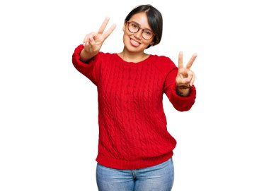 Kısa saçlı, kısa saçlı, gözlüklü, ağzı açık gülümseyen, iki elini de zafer işareti yapan genç ve güzel İspanyol bir kadın. İki numara.. 