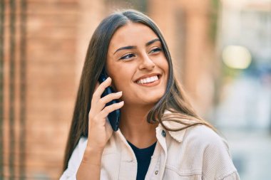 Genç İspanyol kız gülümsüyor. Şehirdeki akıllı telefondan konuşuyor..