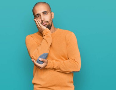 Sıradan bir kazak giyen İspanyol yetişkin bir adam kollarını kavuşturarak depresyondan yorgun ve sıkılmış göründüğünü düşünüyor.. 