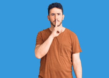 Gündelik kıyafetler giyen genç İspanyol adam parmakları dudaklarında sessiz olmak istiyor. sessizlik ve gizli konsept. 