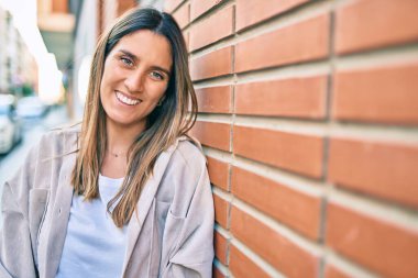 Genç beyaz kadın gülümseyerek şehirde mutlu mesut yürüyor..