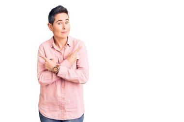 Kısa saçlı, günlük kıyafetler giyen, iki tarafı da parmaklarıyla gösteren genç bir kadın. Farklı yönlere bakıyor. 