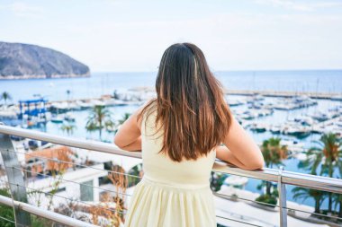 Arkadan bakan genç İspanyol kadın Balustrade görünümlü liman manzarasına yaslanıyor.