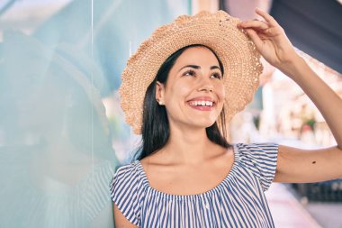 Tatildeki genç Latin turist kız gülümsüyor. Şehrin duvarına yaslanmaktan mutlu..