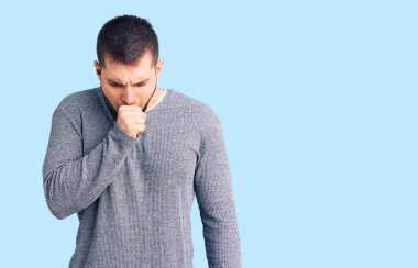 Gündelik kazak giyen genç yakışıklı adam kendini iyi hissetmiyor ve soğuk algınlığı veya bronşitin belirtisi olarak öksürüyor. sağlık hizmeti kavramı. 