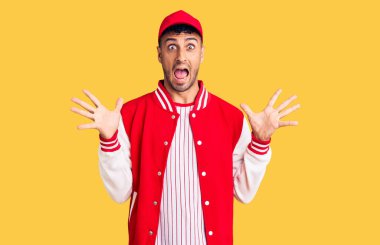 Beyzbol forması giyen genç İspanyol adam çılgınlığı kutluyor ve başarıya hayret ediyor kollarını kaldırıyor ve gözleri açık heyecanla bağırıyor. Kazanan konsept 