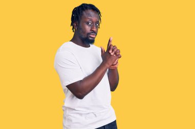 Örgülü, beyaz tişörtlü, el hareketleriyle sembolik silah tutan, cinayet silahlarıyla oynayan, öfkeli yüzlü Afro-Amerikan genç bir adam. 