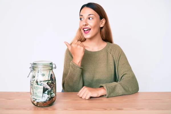 Young Brunette Woman Sitting Table Jar Full Dollars Smiling Happy — Stock fotografie