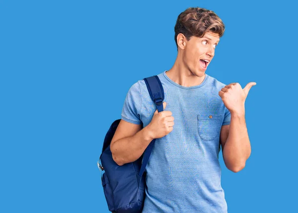 Joven Hombre Guapo Sosteniendo Mochila Estudiante Apuntando Pulgar Hacia Lado —  Fotos de Stock