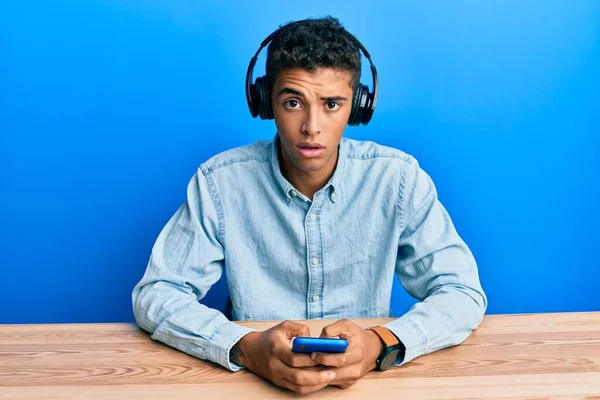Mladý Pohledný Africký Američan Používá Smartphone Sluchátkách Šokujícím Obličeji Vypadá — Stock fotografie