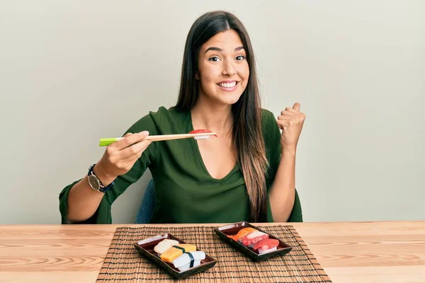 Joven Morena Comiendo Sushi Sentada Mesa Gritando Orgullosa Celebrando Victoria — Foto de Stock