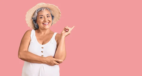 夏の帽子と夏の服を身に着けている灰色の髪を持つシニア女性笑顔幸せなポインティングで手と指で側面 — ストック写真