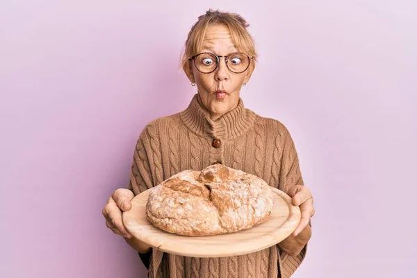 Orta Yaşlı Sarışın Kadın Elinde Ekmek Tutarken Balık Suratlı Şaşı — Stok fotoğraf