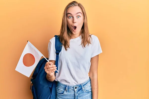 Hermosa Mujer Rubia Estudiante Intercambio Sosteniendo Bandera Japón Asustada Sorprendida —  Fotos de Stock