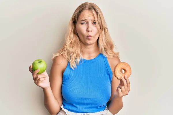 Молода Блондинка Тримає Зелене Яблуко Пончик Робить Риб Яче Обличчя — стокове фото