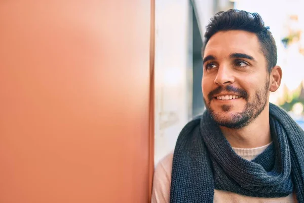 Joven Hombre Hispano Sonriendo Feliz Usando Bufanda Apoyada Pared Ciudad —  Fotos de Stock