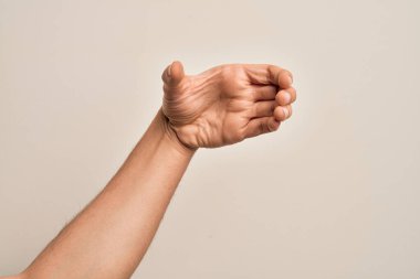 Beyaz tenli bir gencin eli, görünmeyen bir nesneyi tutan beyaz arka plan üzerinde parmaklarını gösteriyor. Elleri boş, kesme ve yakalama hareketi yapıyor.