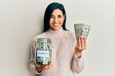 Genç beyaz bir kadın bağış kavanozu ve dolar banknotları tutuyor. Gülmekten kırılıyor ve kahkahalarla gülüyor.. 