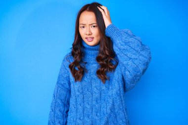 Kış süveteri giyen genç ve güzel bir Çinli kız soru sormayı merak ediyor. Şüpheyle kararsız, kafa kafaya düşünerek. Düşünceli kavram. 