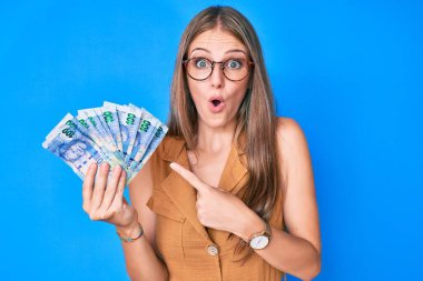 Güney Afrika rand 'ini elinde tutan genç sarışın kız şaşırmış ve şaşırmış bir ifade, korku ve heyecanlı bir yüz ifadesiyle paralar.. 