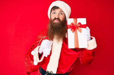 Uzun sakallı, yakışıklı kızıl saçlı, Noel Baba kostümü giyen ve kameraya bakıp öpüşen sevimli ve seksi bir adam. aşk ifadesi. 