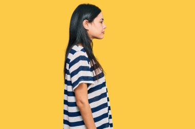 Güzel, genç bir kadın, günlük giysiler içinde rahat bir görünüm takınıyor, doğal bir yüz ifadesi ve kendine güvenen bir gülümsemesi var.. 