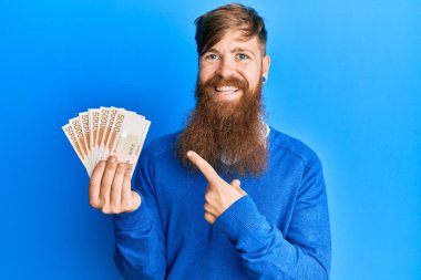 5000 Güney Koreli 'yi tutan genç İrlandalı kızıl adam mutlu bir şekilde el ve parmak işareti yaparak para kazandı. 