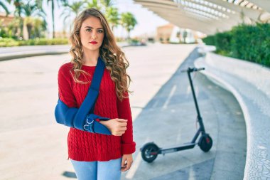 Parkta dikilen kol askısıyla ciddi bir şekilde yaralanmış genç sarışın kız..