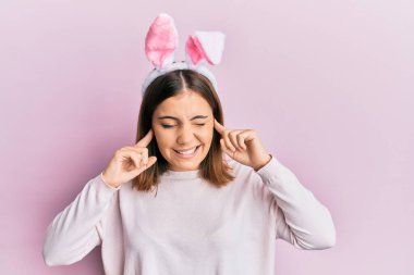 Hoş paskalya tavşanı kulakları takan genç ve güzel bir kadın yüksek sesli müzik sesi için parmaklarıyla kulaklarını kapatıyor. sağır kavramı. 